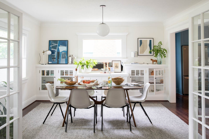 A bright dining room with a globe pendant over the table. 
